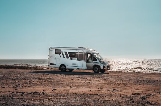 Carado Wohnmobil in Seitenansicht auf felsigem Küstenplatz am Meer